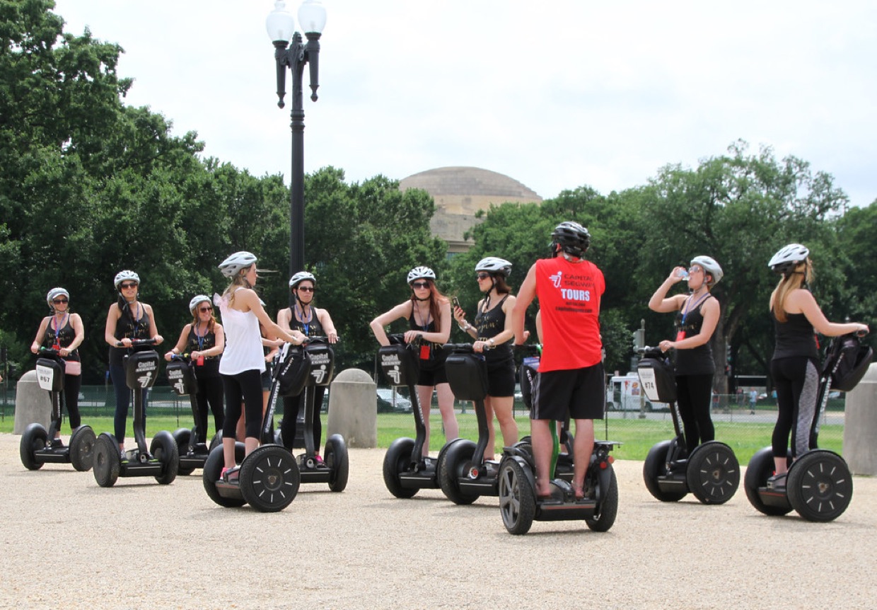 A guided Segway tour in Washington DC: a dozen riders in helmets, lined up behind a guide in a red vest.